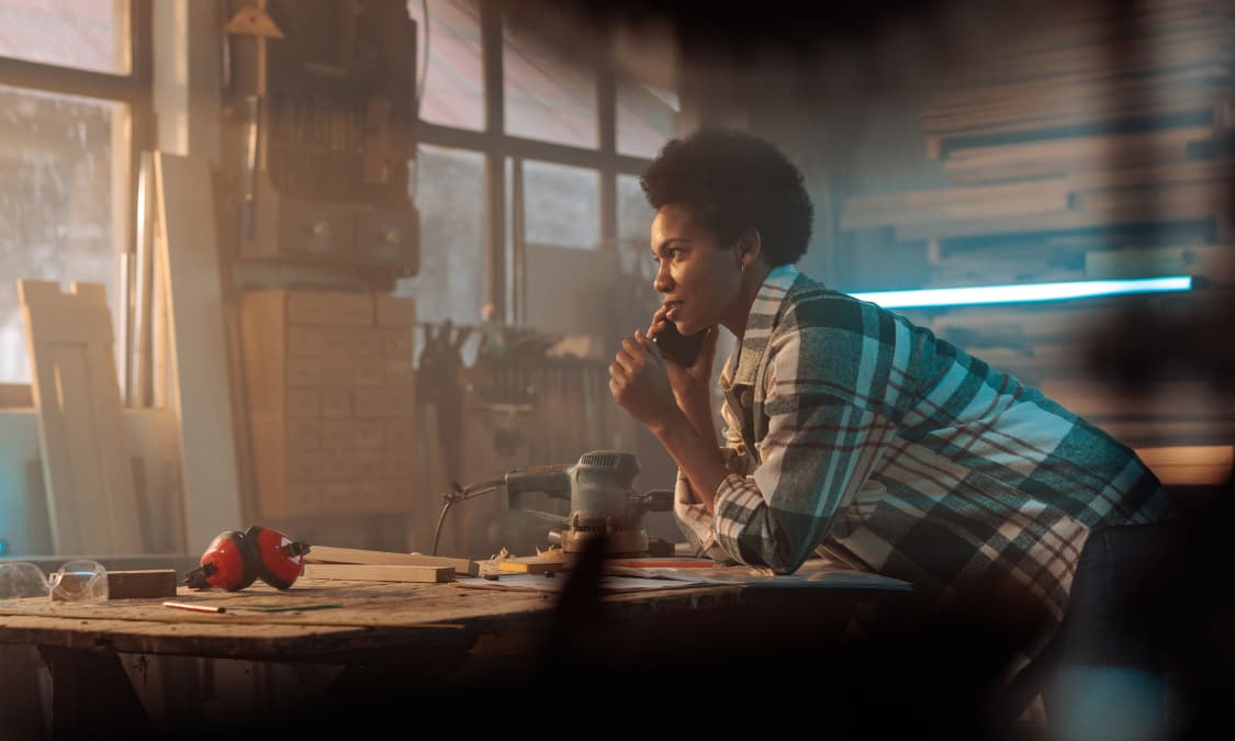 A young African American woman on the phone in a workshop.