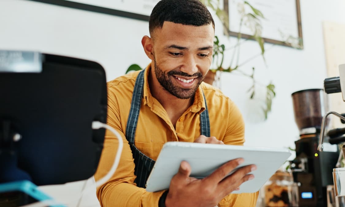 A happy young African American man on a tablet.