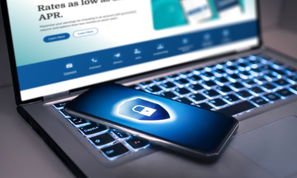 A mobile phone with a glowing padlock on the lock screen resting on a laptop.